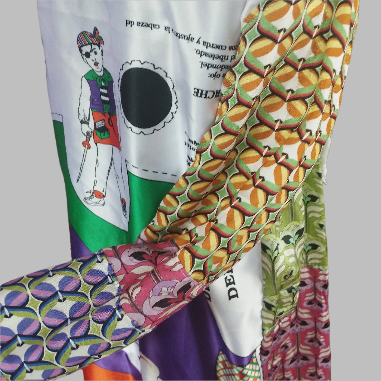 Close-up view of a vibrant, intricately designed fabric detail from an upcycled vintage kimono-style coat. Features bold yellow lace patterns, colorful floral embroidery, and a mix of rich, festive prints inspired by Canarian carnival aesthetics. A striking combination of textures and colors for a unique, eye-catching garment.